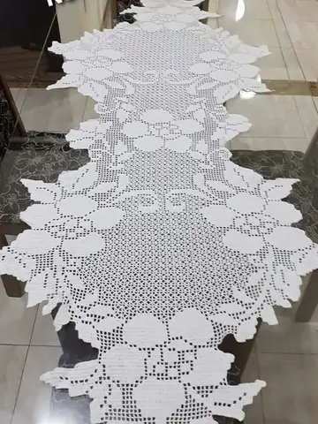 Caminho de mesa branco de crochê filet com flores, sobre mesa de vidro