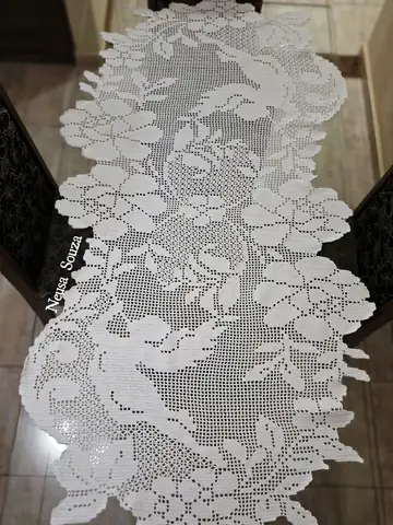 Caminho de mesa branco de crochê filet com pássaros e flores, sobre mesa de vidro